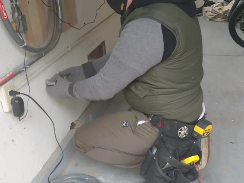 Electrician performing outlet wiring in a Brent garage